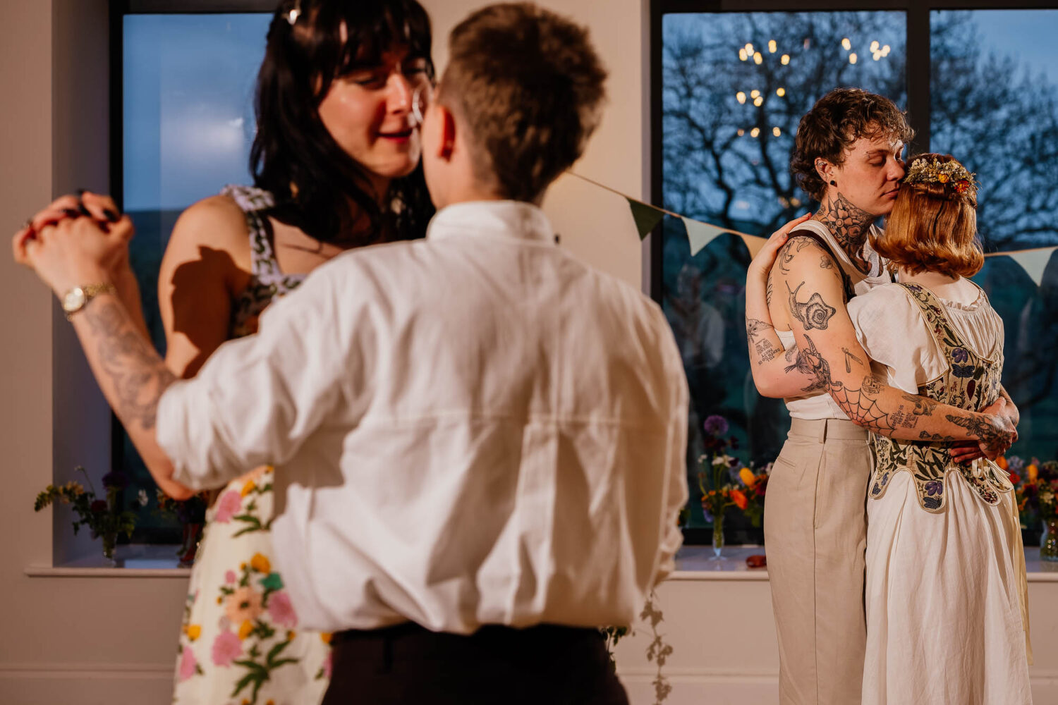 Two couples dancing together in blue hour with windows behind