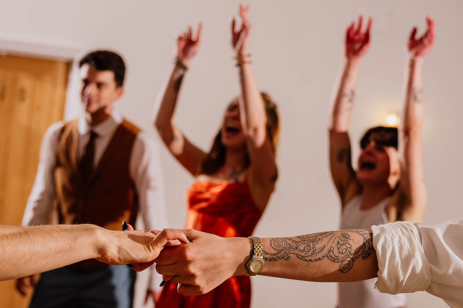 Hands holding in the foreground with people with their arms in the air behind