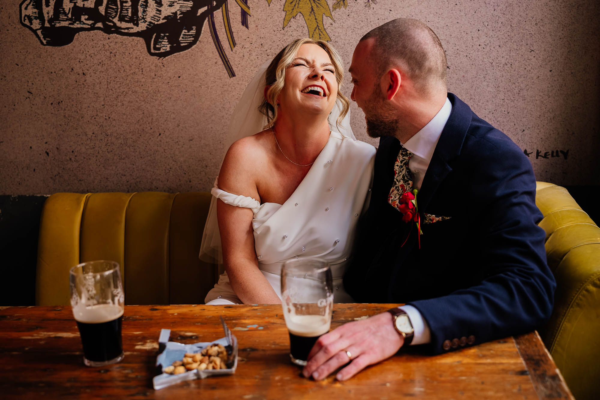 Couple portrait in pub with pints of Guinness and pork scratchings on the table