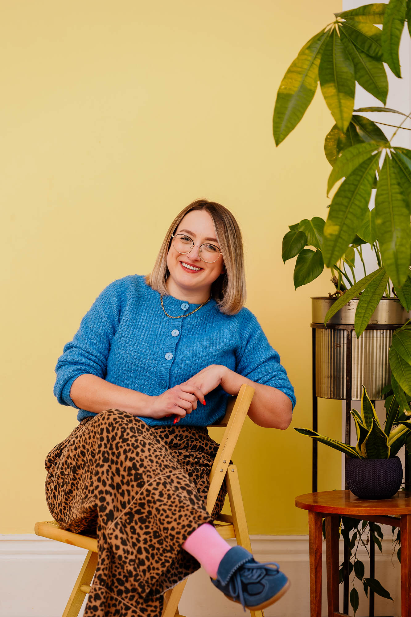 Branding photos of woman sat on chair wearing blue against a yellow wall