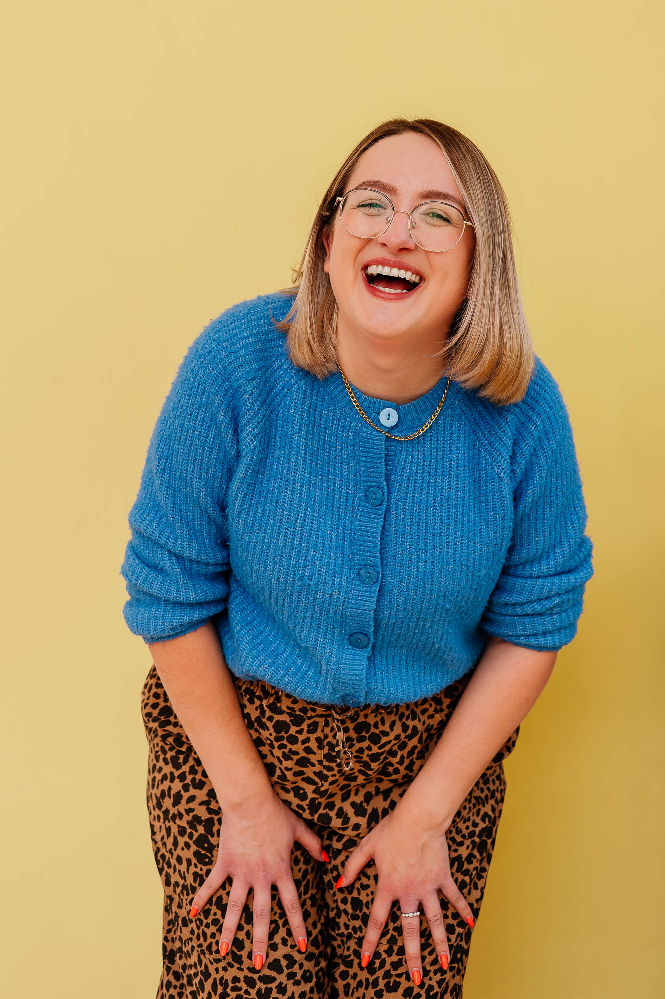 Business owner headshot laughing against a yellow wall