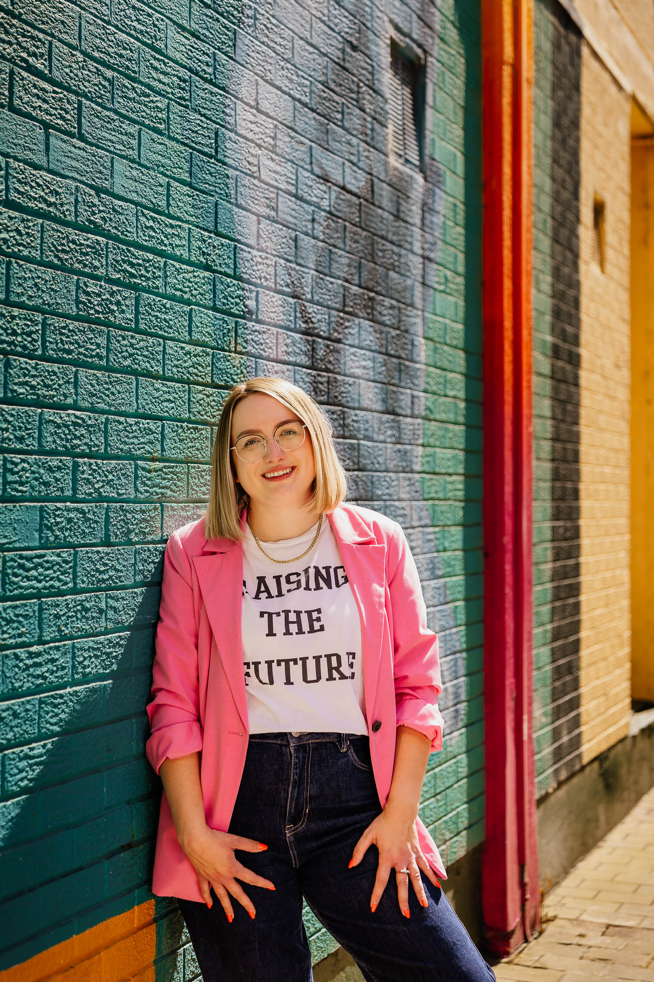 Portrait of woman in pink blazer against a blue wall