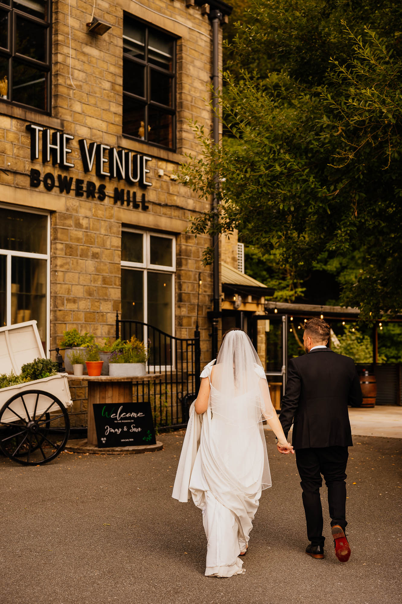 Bride and groom walking hand in hand towards The Venue in Halifax