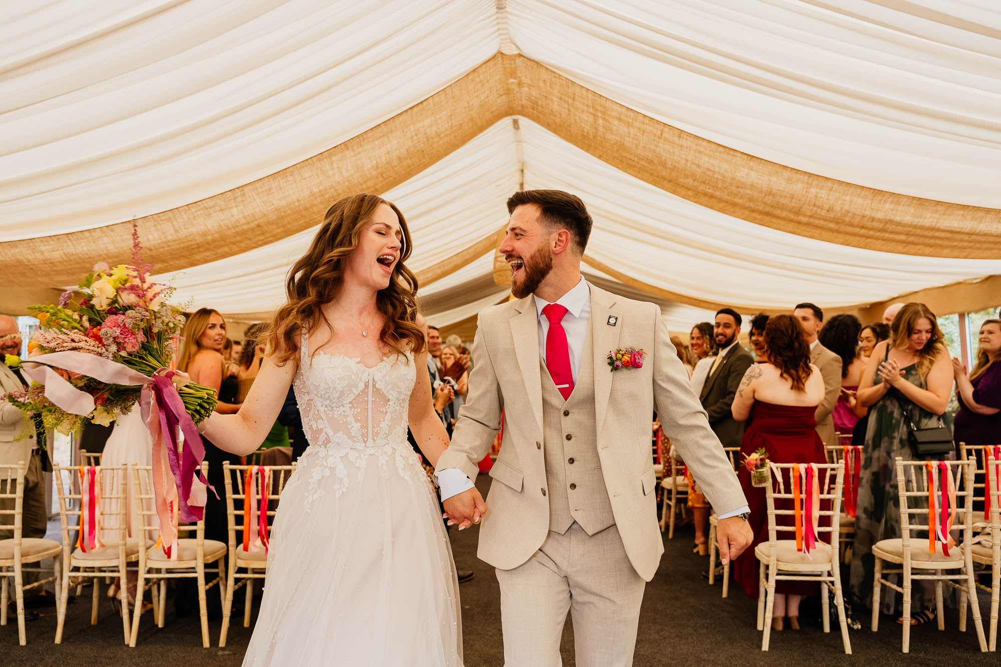 Couple singing and dancing whilst walking down the aisle at The Woodman Inn wedding